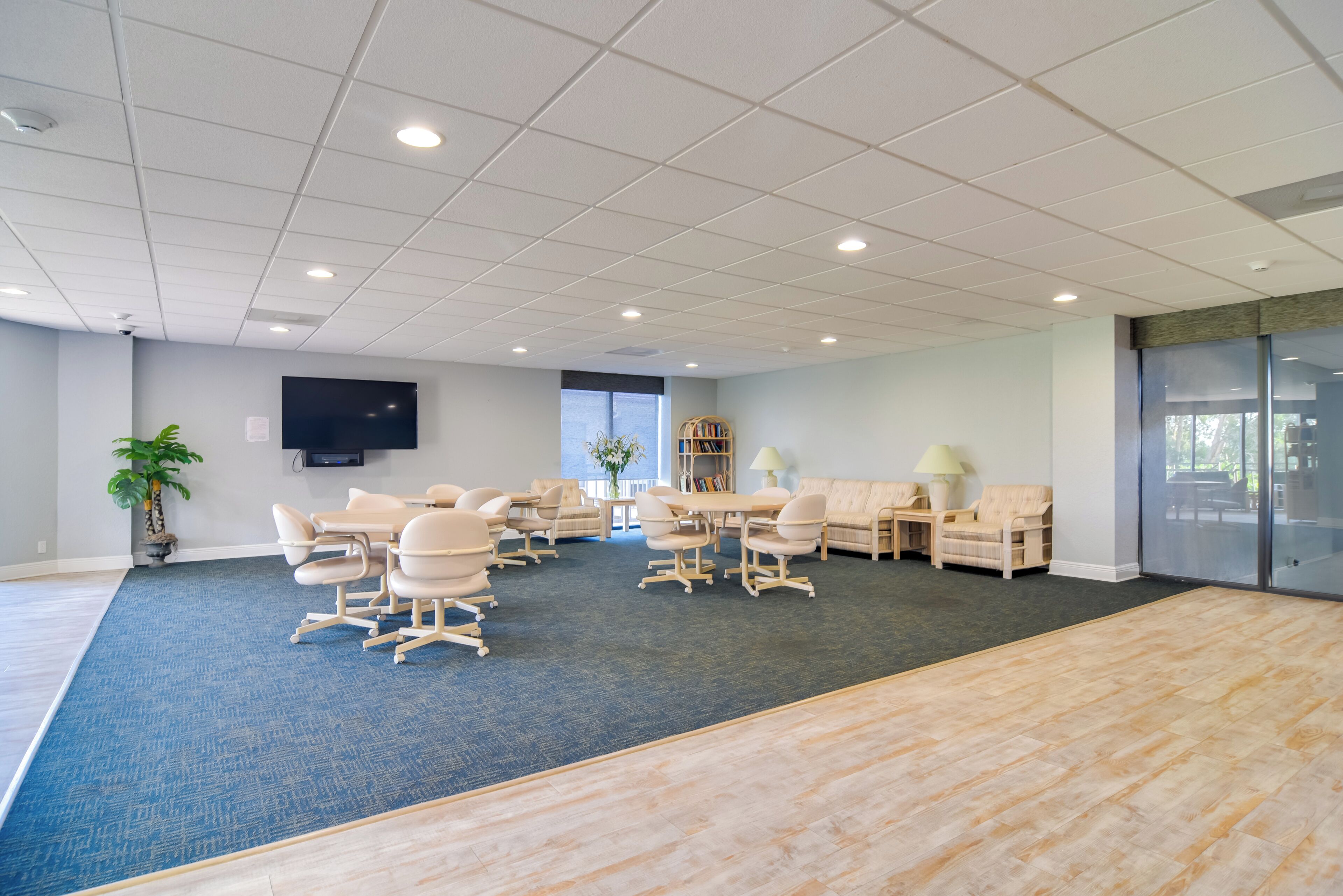 Une salle de conférence spacieuse, dotée d’une grande table, de nombreuses chaises, d’un canapé et d’un téléviseur fixé au mur.
