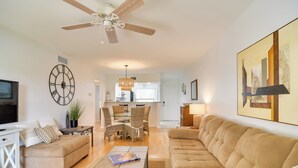 A spacious living room with a sofa, coffee table, and TV. There is a dining area with a table and chairs, and a kitchen in the background. - ~ 2 Mi to St Pete Beach! Isla Del Sol Condo (St. Petersburg)