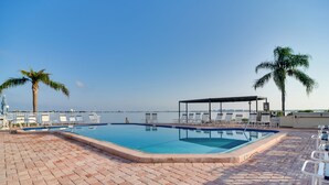 A pool area with lounge chairs and a covered seating area, overlooking a body of water. - ~ 2 Mi to St Pete Beach! Isla Del Sol Condo (St. Petersburg)