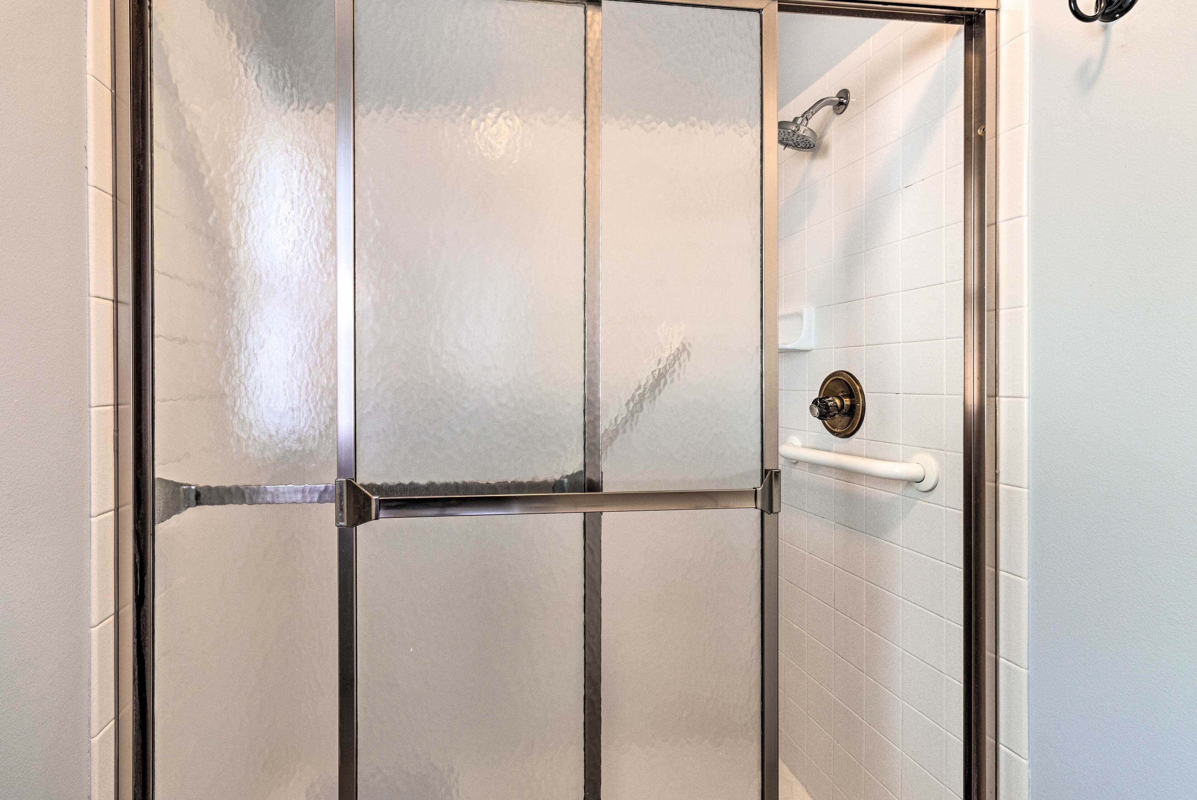 A shower enclosure with frosted glass doors, a handheld showerhead, and a wall-mounted faucet.