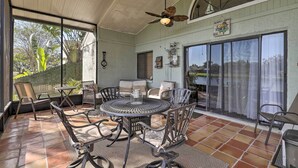 A covered patio with a round table and chairs, large windows, and a ceiling fan. - Lakefront Brandon Home w/ Patio & Screened Lanai! (Brandon)