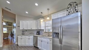 A modern kitchen with white cabinets, stainless steel appliances, and a tiled floor. - Lakefront Brandon Home w/ Patio & Screened Lanai! (Brandon)