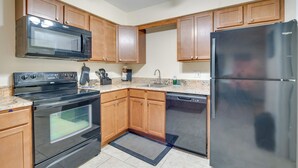 A kitchen with wooden cabinets, a black microwave, a black stove, a black refrigerator, and a dishwasher.