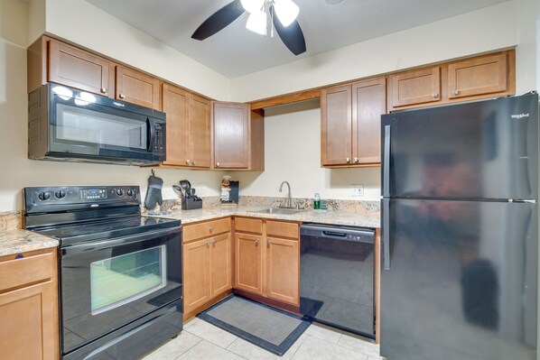 A kitchen with wooden cabinets, a black microwave, a black stove, a black refrigerator, and a dishwasher. - Lovely Ocala Vacation Rental Apartment! (Ocala)