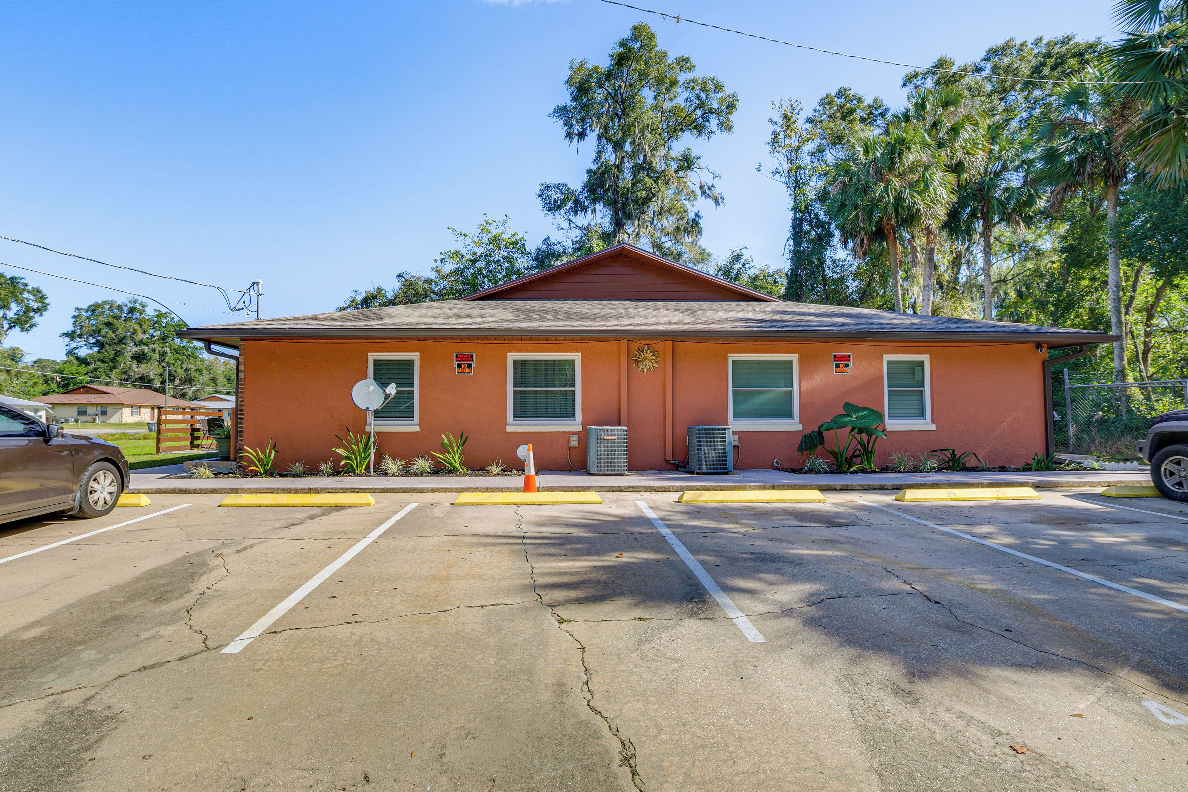 A two-story building with a red facade, a parking lot with yellow curbs, and a street in the background.