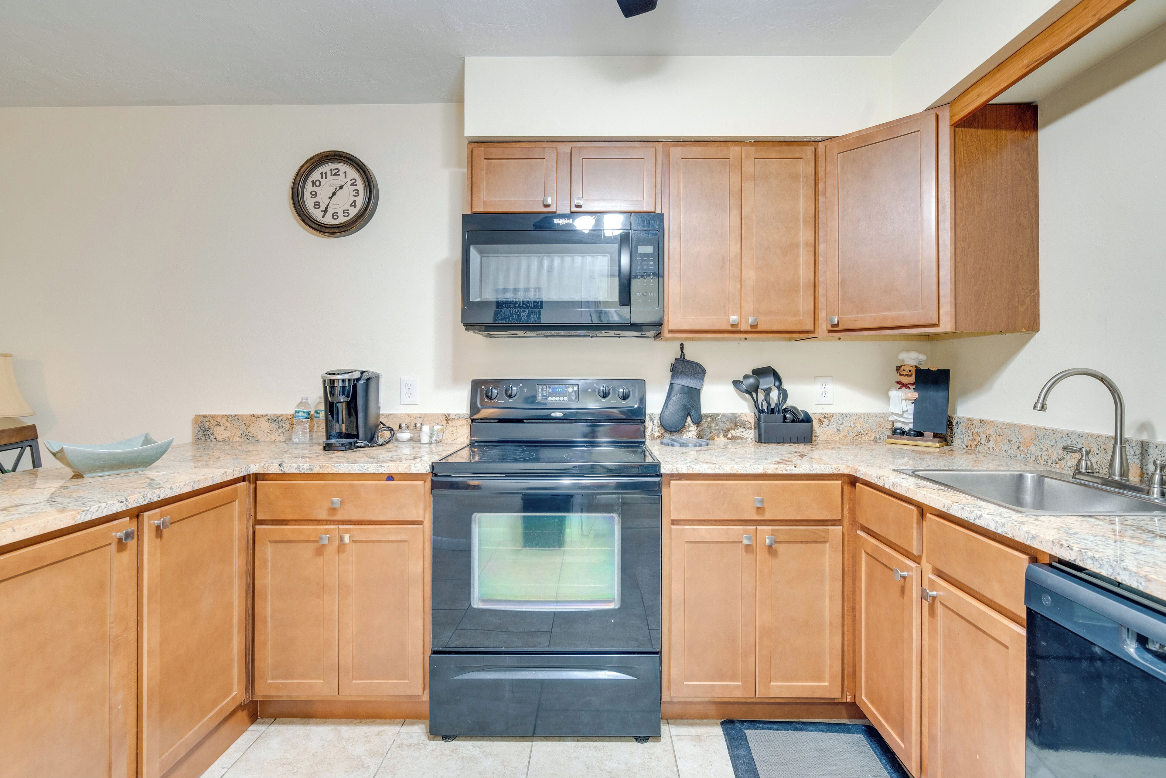 A kitchen with wooden cabinets, a black stove, a microwave, and a sink.