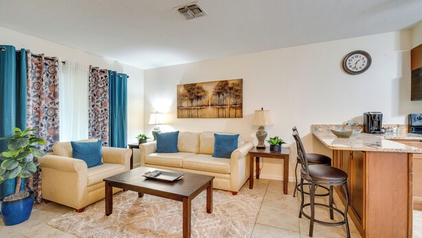 A living room with a beige sofa, a coffee table, a small rug, a lamp, and a painting on the wall.