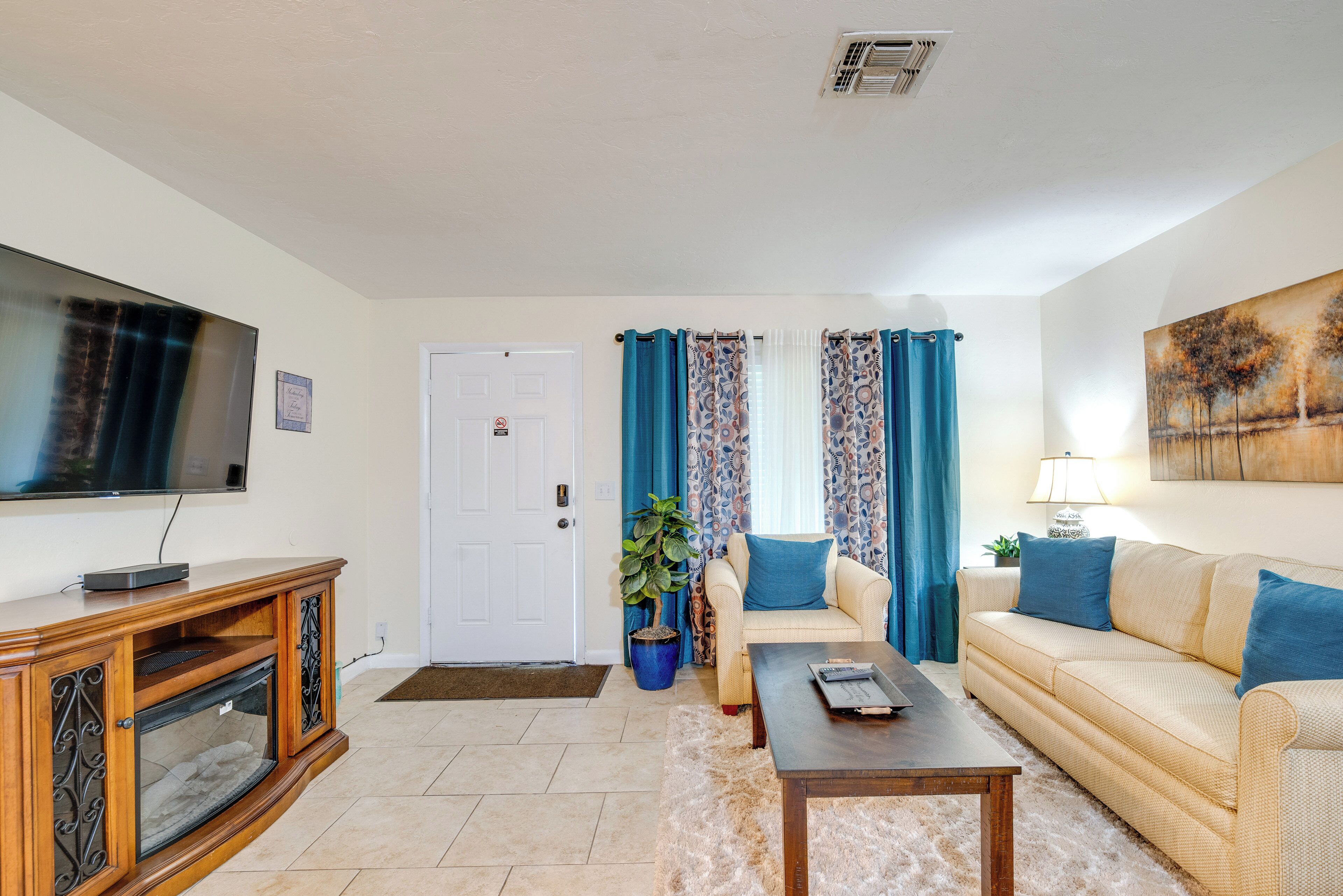 A living room with a television, sofa, coffee table, and a potted plant.
