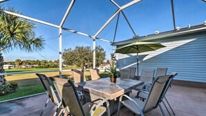 Eine überdachte Terrasse mit Tisch, Stühlen, einer Topfpflanze und einem Sonnenschirm.