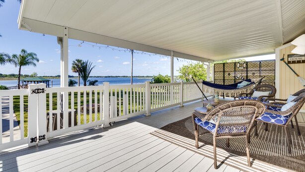 A covered outdoor area with wicker furniture and a view of the water.