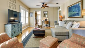A living room with a television, sofa, ottoman, and decorative items.