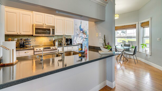 A kitchen with white cabinets, stainless steel appliances, and a large island with a sink. - Paddle, Bike & Relax! Canal-front Cape Coral Home (Cape Coral)