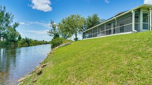 A riverside building with a grassy slope and a clear view of the water. - Paddle, Bike & Relax! Canal-front Cape Coral Home (Cape Coral)