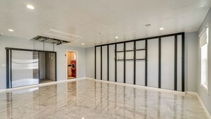 A spacious, modern room with a polished marble floor, a large sliding glass door, and a minimalist wall design. - Paddle, Bike & Relax! Canal-front Cape Coral Home (Cape Coral)
