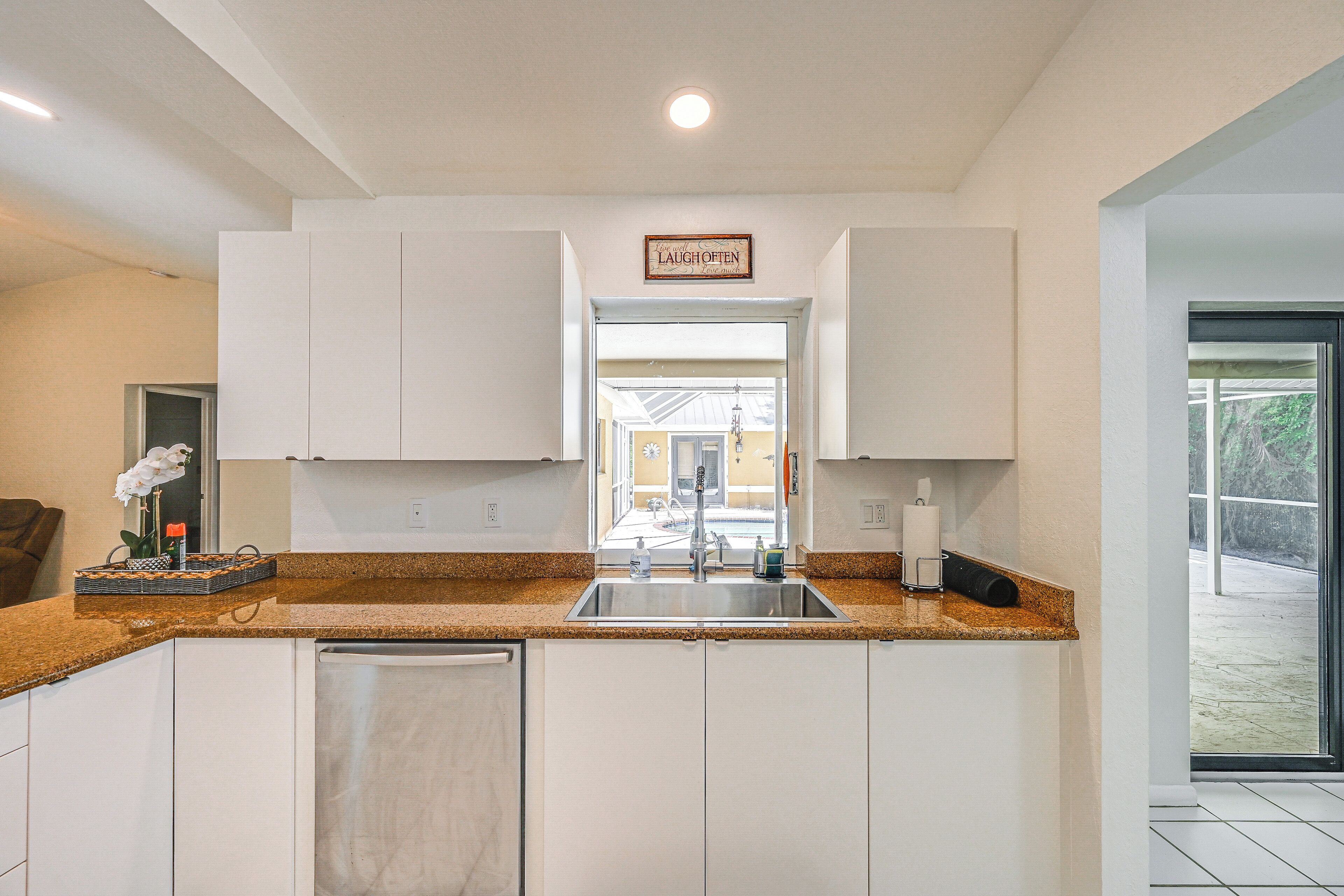 A modern kitchen with white cabinets, a granite countertop, and a stainless steel sink.