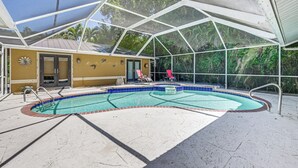 An indoor swimming pool with a covered area, a poolside lounge, and a view of the surrounding greenery. - Lovely Naples Home: Backyard Oasis w/ Pool! (Naples)