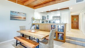 A dining area with a wooden table and benches, a kitchen with white cabinets and stainless steel appliances, and a staircase leading to an upper level.