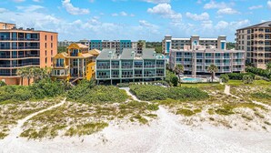 A beachfront hotel with multiple buildings, a pool, and a sandy beach area.