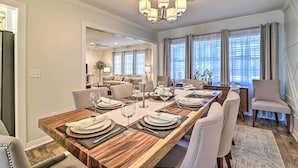 A dining area with a long wooden table set for six, surrounded by six upholstered chairs. - Mid-century Modern Escape in Central Lakeland! (Lakeland)