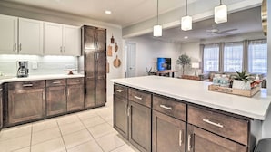 A modern kitchen with dark cabinets, a large island, and pendant lighting. - Mid-century Modern Escape in Central Lakeland! (Lakeland)