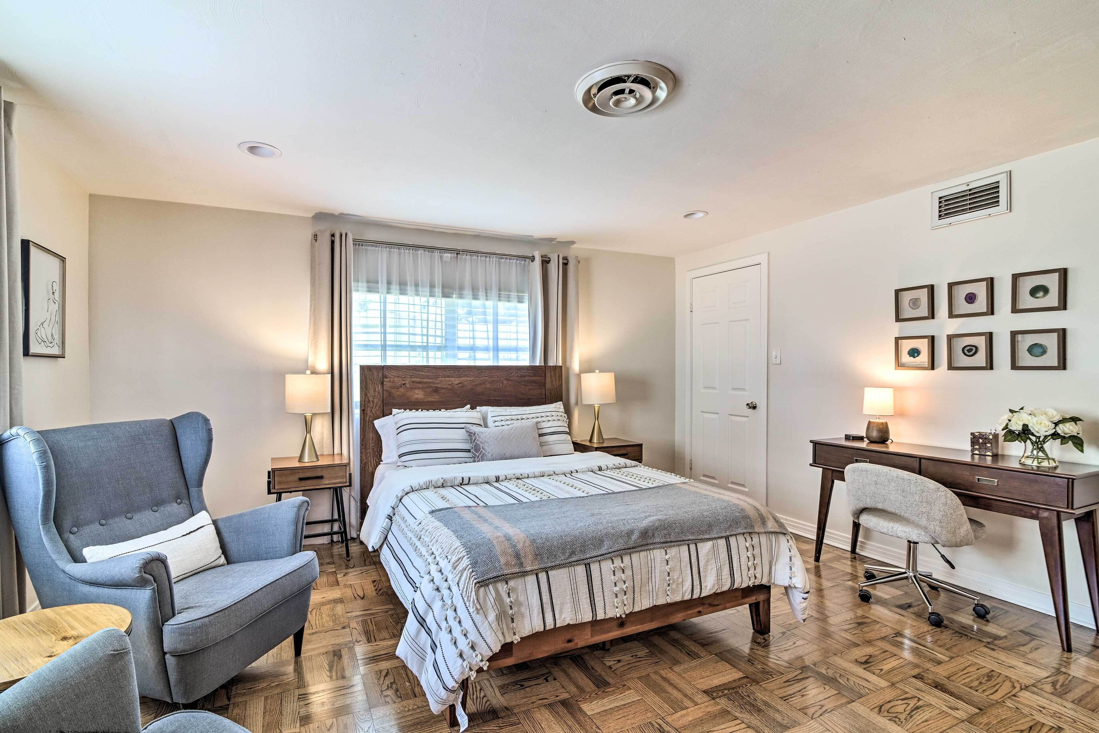 A bedroom with a bed, a desk, a chair, and a nightstand.