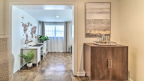 A hallway with a wooden floor, a desk with a potted plant, a cabinet with kitchen items, and a world map on the wall. - Mid-century Modern Escape in Central Lakeland! (Lakeland)