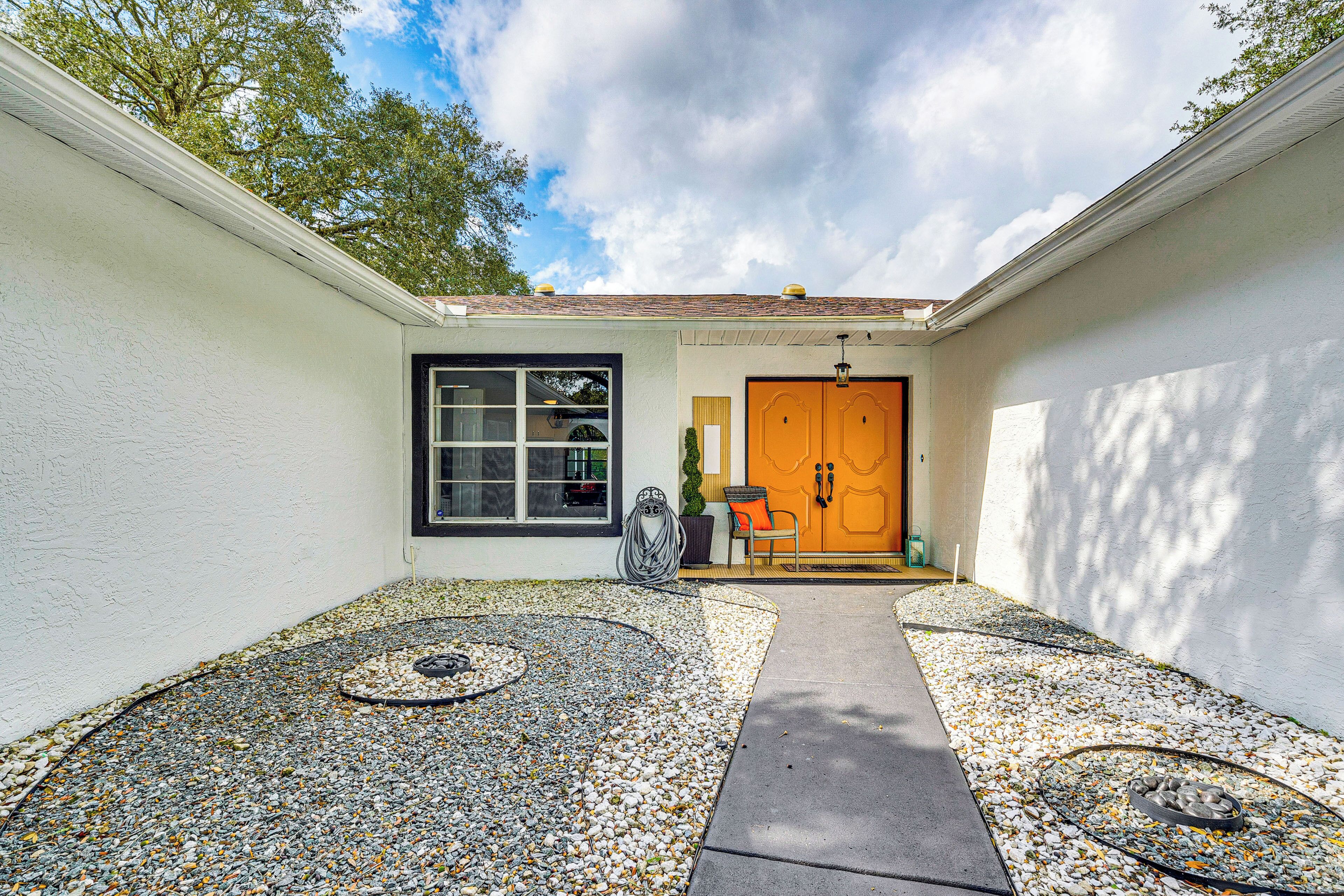 A house with a white exterior, a black-framed window, and an orange door.