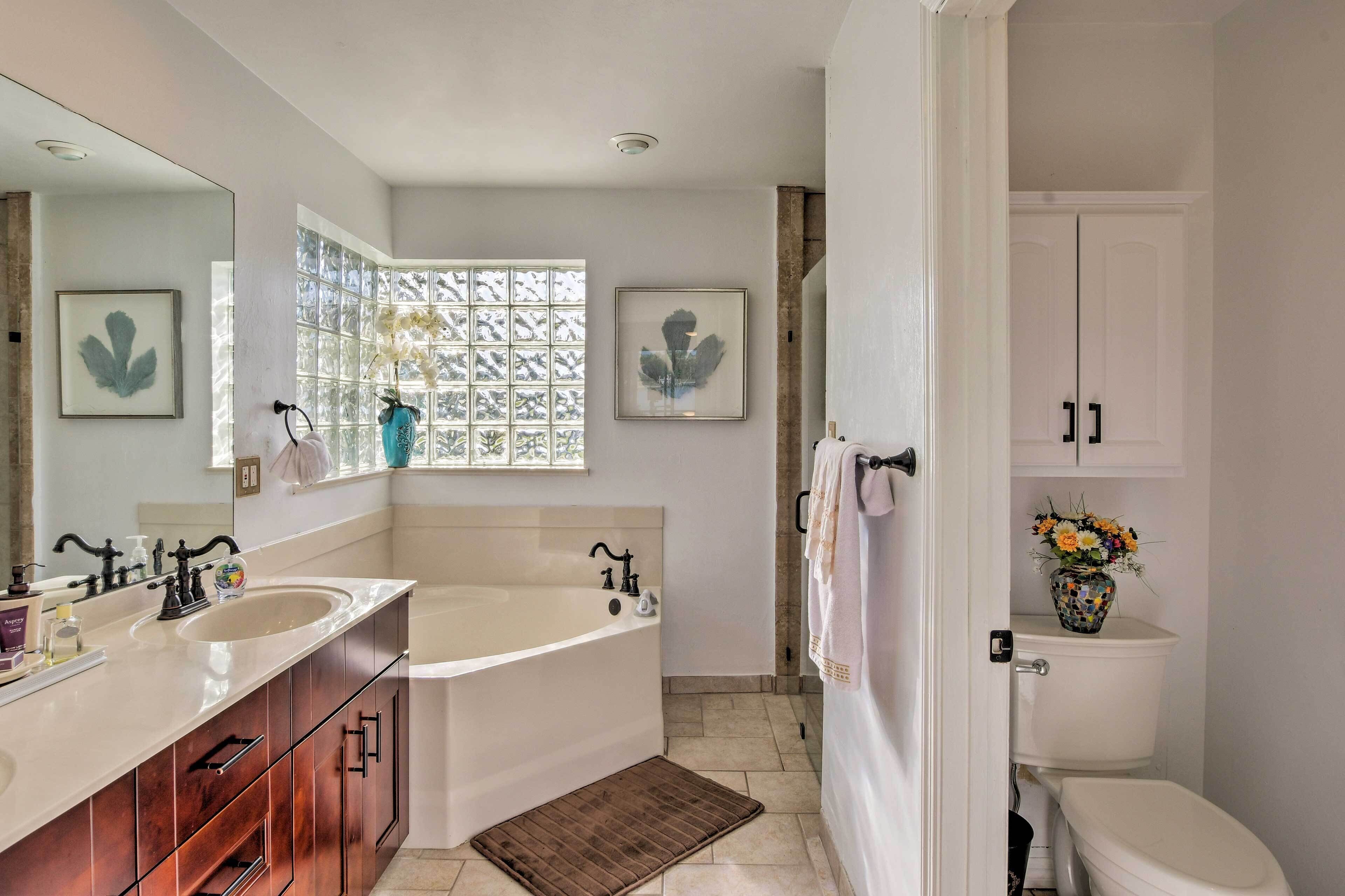 A modern bathroom with a large bathtub, double sinks, and a toilet.