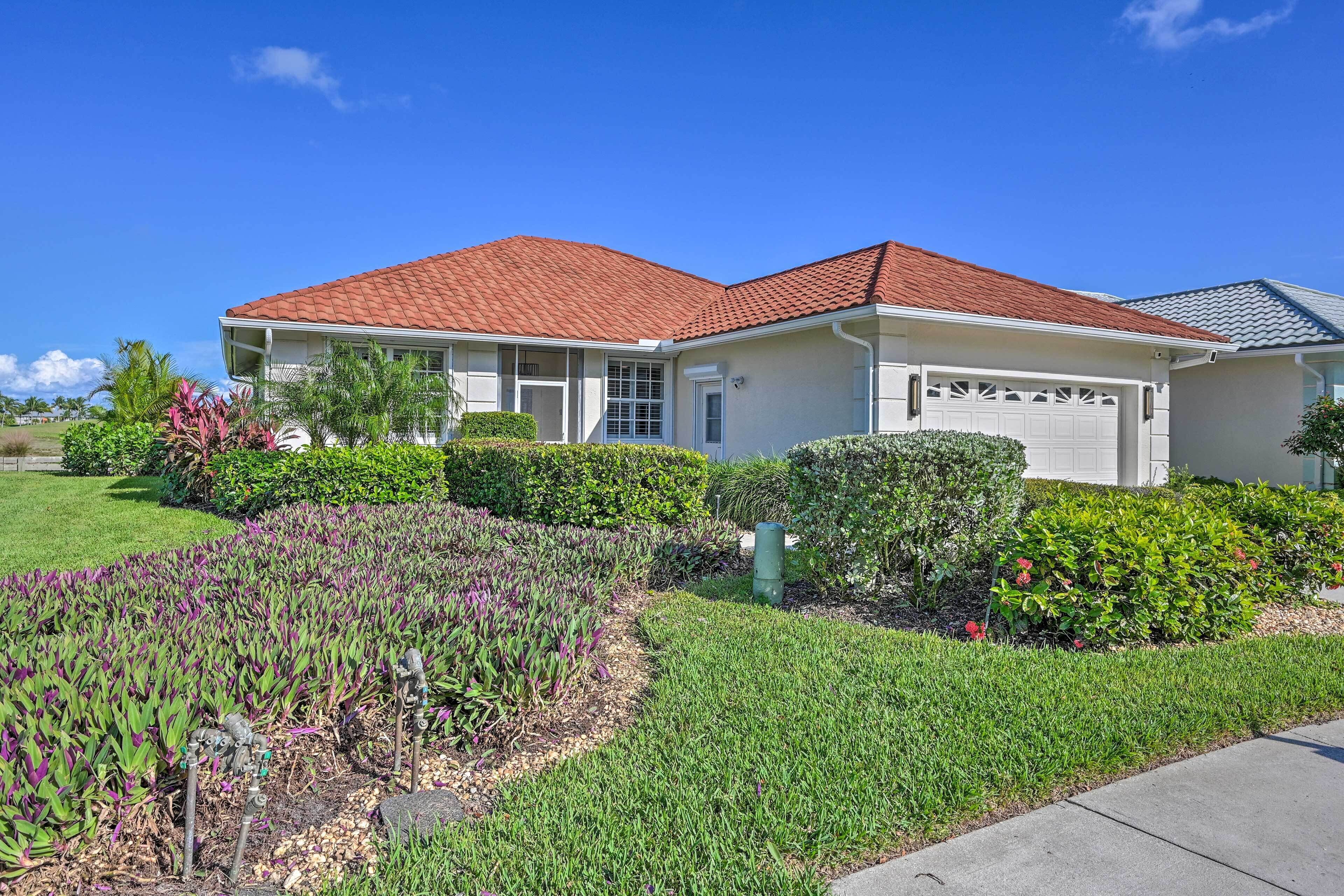 A single-story house with a red-tiled roof, a front garage, and a well-maintained garden with various plants and shrubs.