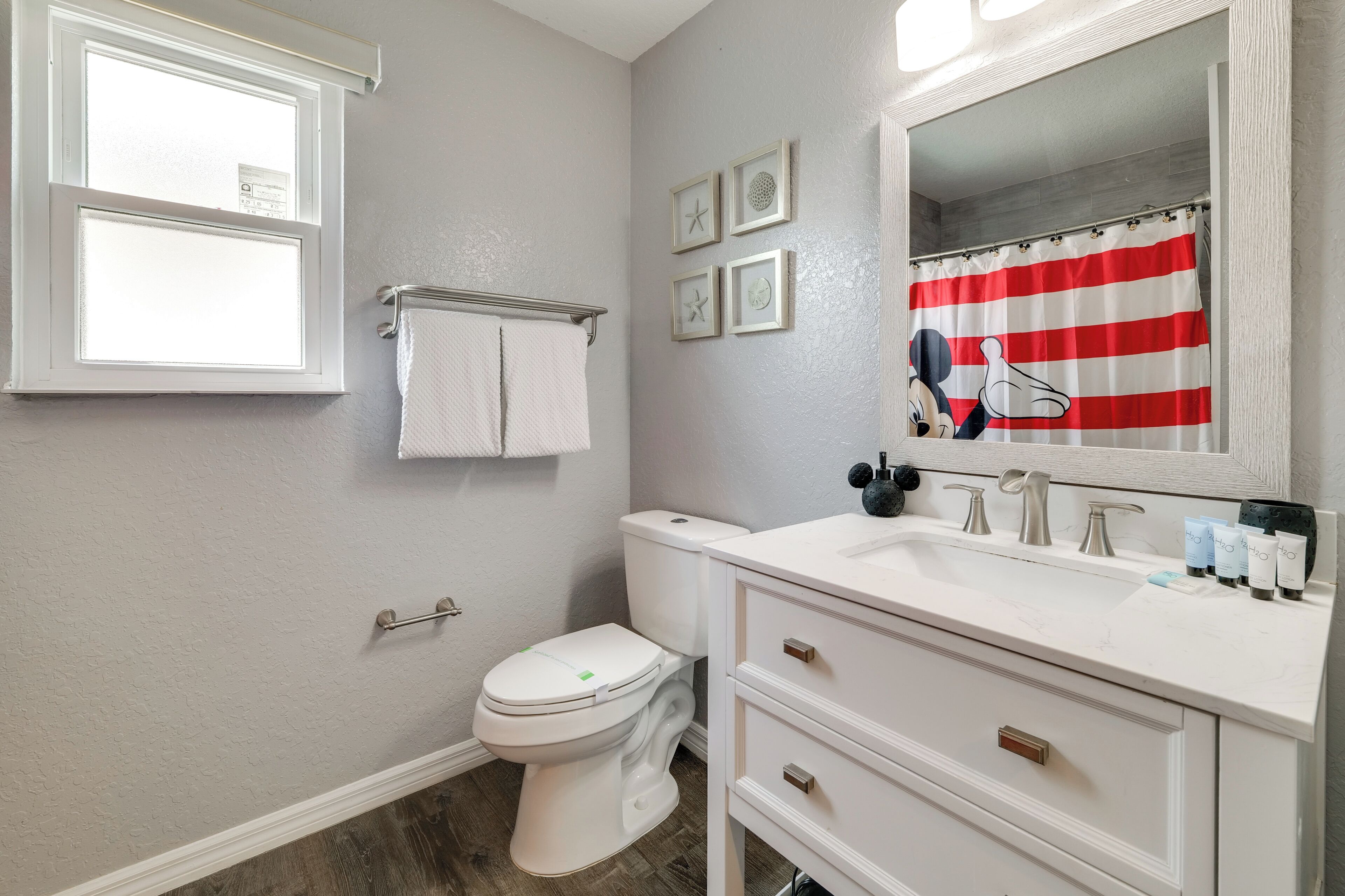 Une salle de bain comprenant des toilettes, un lavabo, un meuble-lavabo et un miroir.