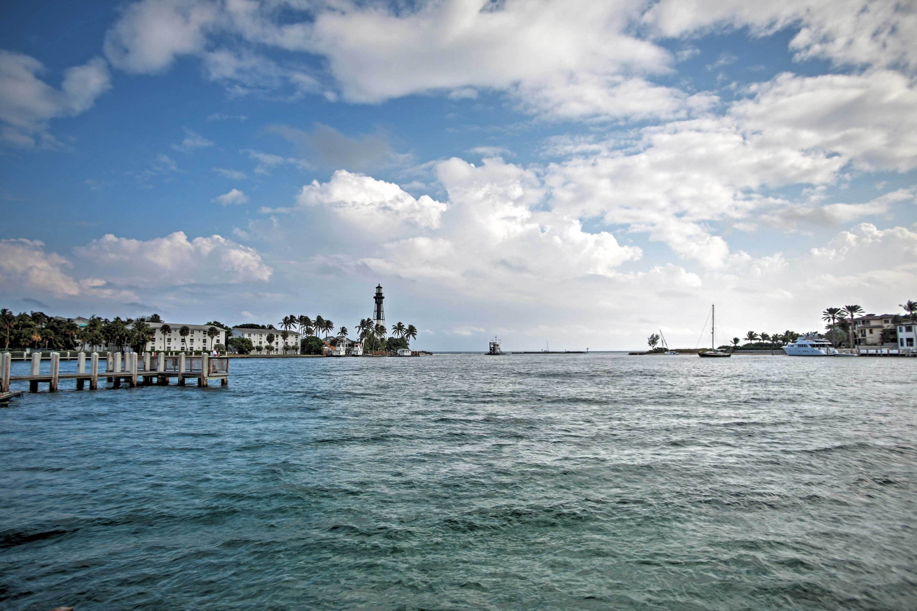 A waterfront view with a pier, buildings, and a lighthouse.