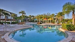 A pool area with lounge chairs, palm trees, and a gazebo.