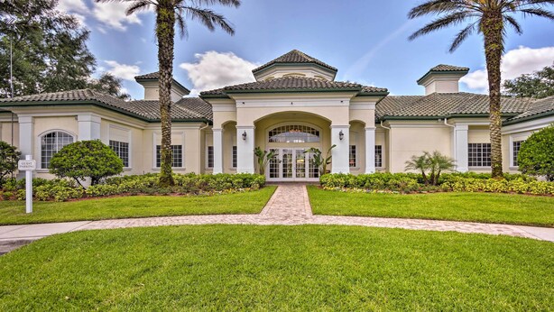 A large, two-story building with a symmetrical facade, a central entrance with a portico, and a paved driveway leading to the entrance.