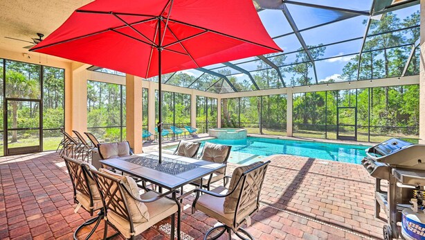 Um pátio externo com piscina, churrasqueira e mesa com cadeiras.