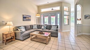 Uma sala de estar com um sofá modular, uma mesa de centro e uma luminária. Há uma janela com vista para o exterior.