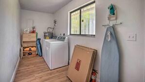A laundry room with a washing machine, ironing board, and a window with blinds. - Naples Home w/ Private Pool: 6 Mi to Dtwn! (Naples)