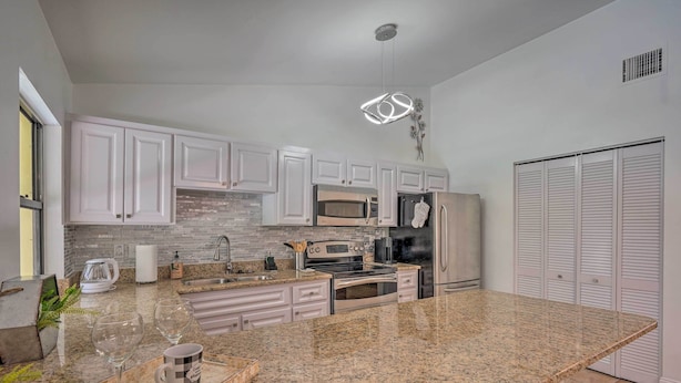 A modern kitchen with white cabinets, granite countertops, stainless steel appliances, and a built-in oven. - Naples Home w/ Private Pool: 6 Mi to Dtwn! (Naples)