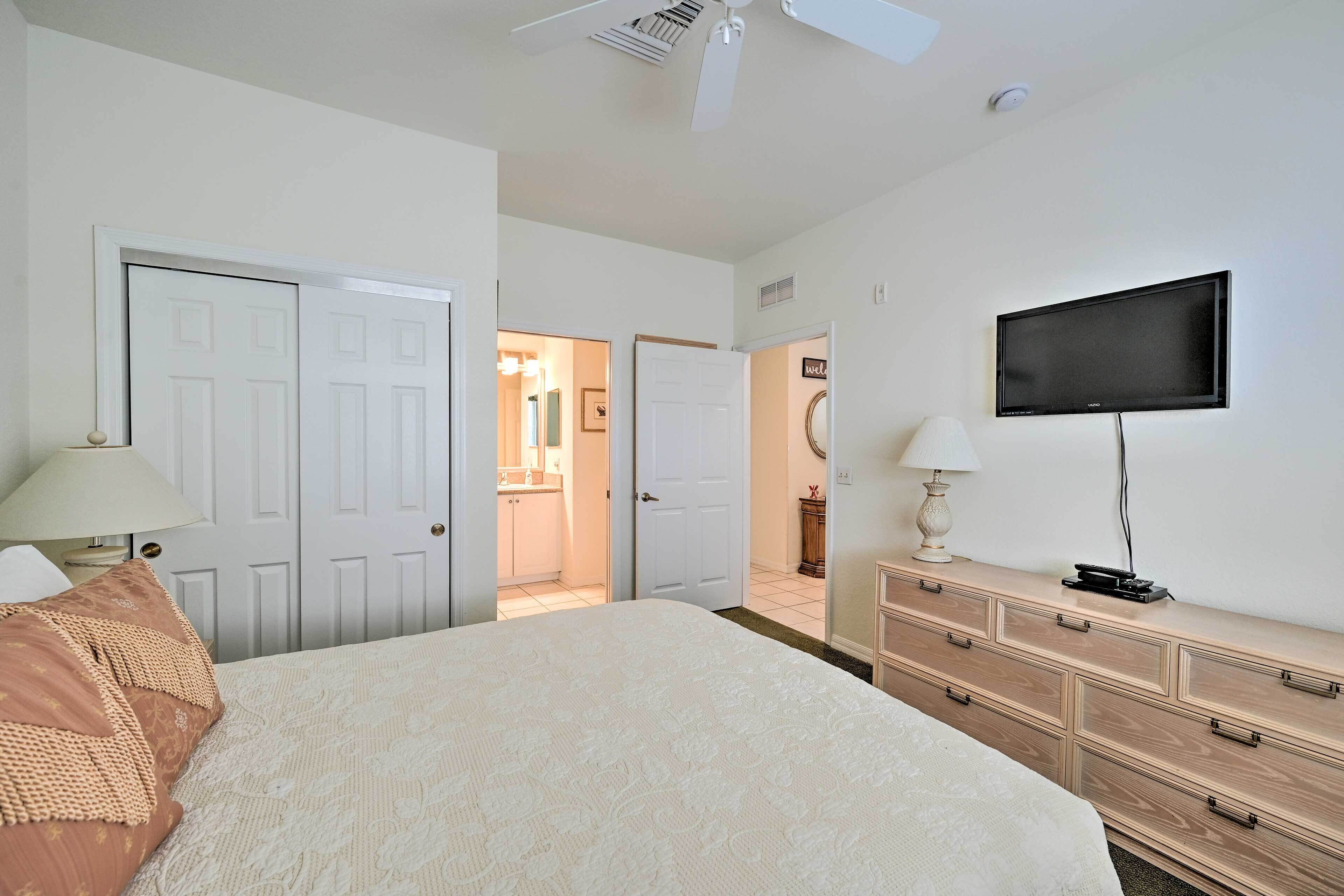 A bedroom with a bed, a dresser, a television, and a ceiling fan.