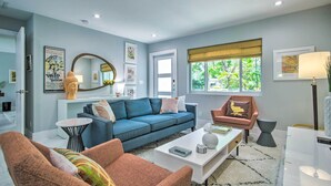 A modern living room with a blue sofa, a pink armchair, and a white coffee table. - Modern Wilton Manors Home w/ Outdoor Oasis! (Wilton Manors)