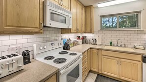 Una cocina moderna con armarios de madera, una estufa blanca, un microondas y un lavamanos.