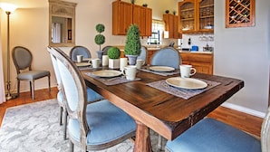A dining room with a wooden table set for four, surrounded by blue upholstered chairs.