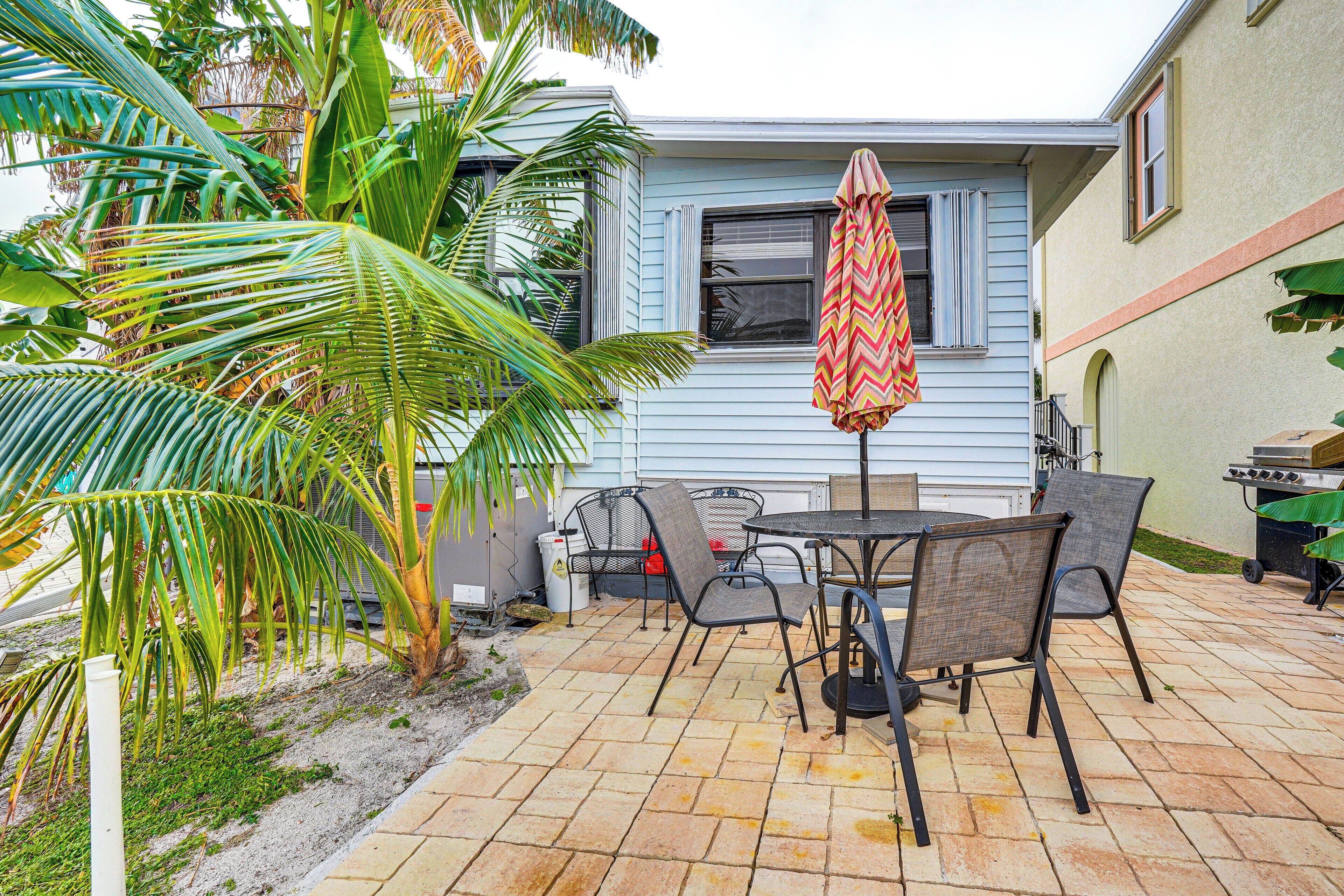 A patio with a table and chairs, a grill, and a house in the background.