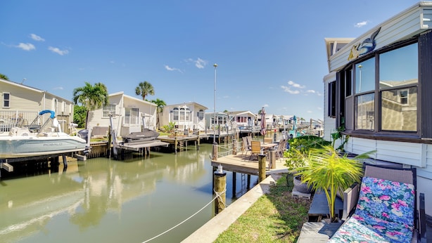 A marina with boats docked, a row of mobile homes, and a house with a large window. - Nettles Island Vacation Rental w/ Resort Amenities (Jensen Beach)