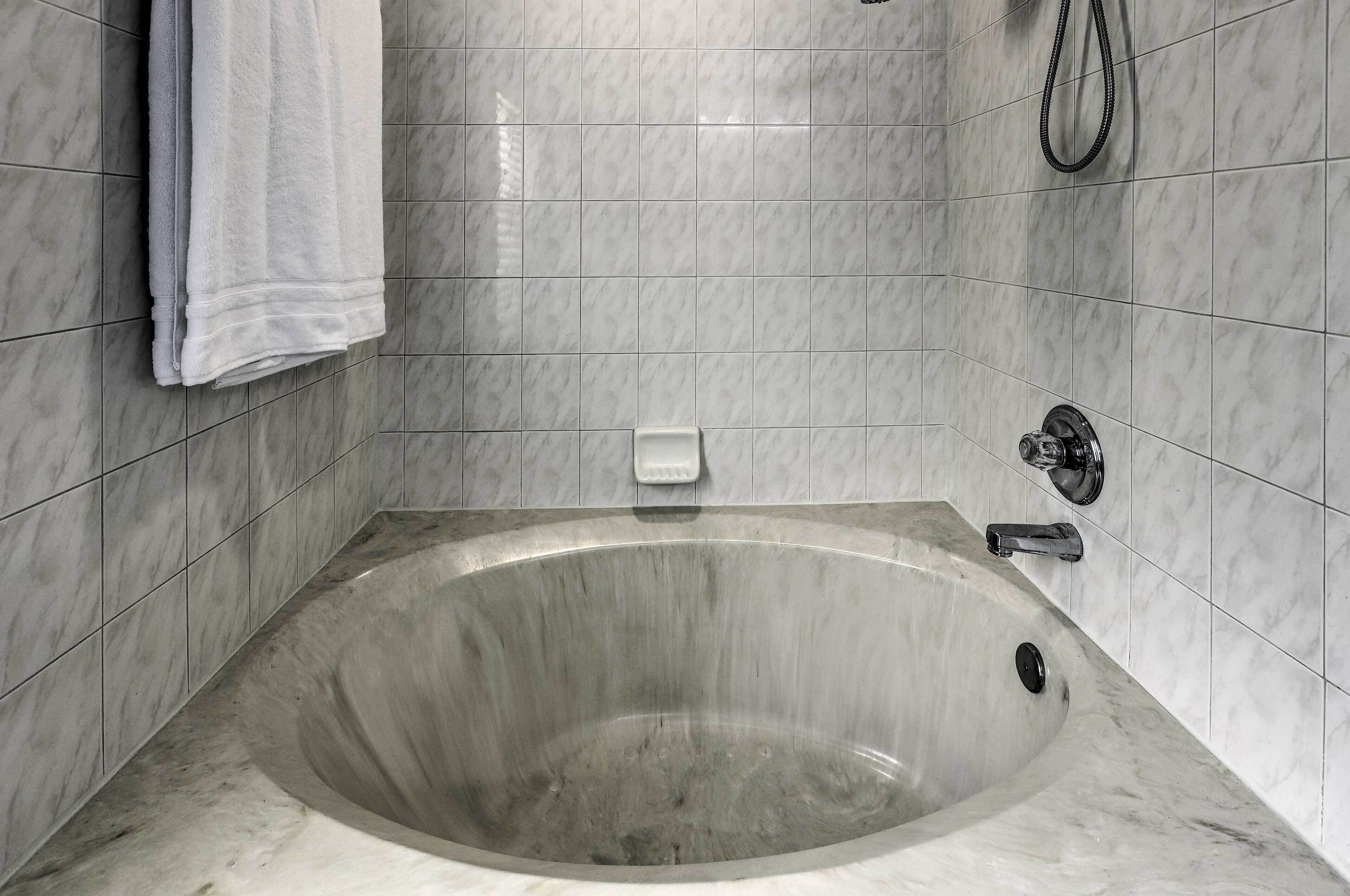 A modern bathroom with a freestanding bathtub, a handheld showerhead, and a towel rack.
