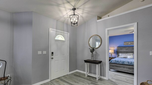 Un dormitorio con cama, mesita de noche, espejo y puerta.