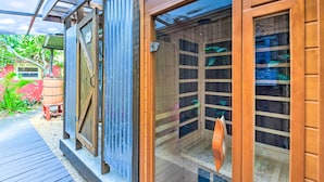 A wooden spa structure with glass doors, a wooden deck, and a small outdoor seating area.
