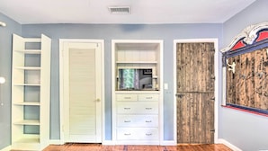 A bedroom with a wooden floor, a patterned rug, a bed, a wardrobe with a mirror, and a door with a wooden panel.