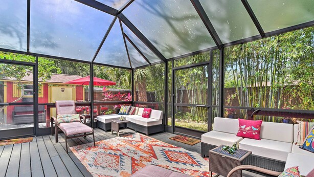 A covered outdoor area with a wooden deck, a sofa set, and a dining table.