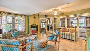 A spacious living area with a high ceiling, a ceiling fan, and a view of the backyard through large windows.