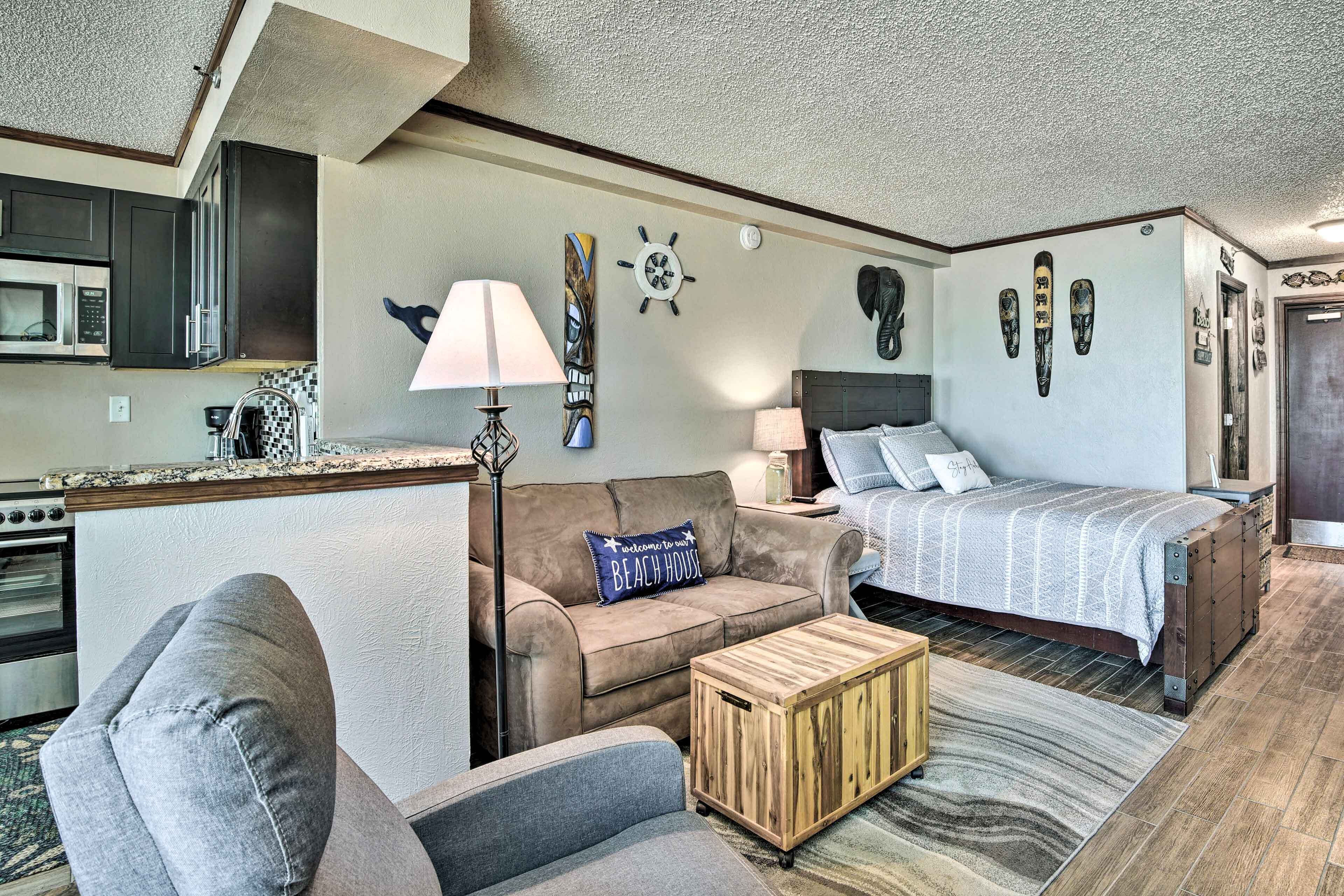A compact living space with a kitchenette, a sofa, a bed, and a coffee table.